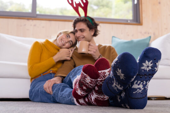 Christmas time, Cozy couple relaxing at home, wearing festive socks and drinking hot cocoa
