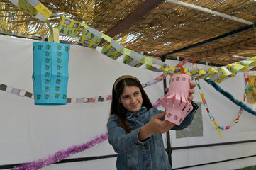 Jewish teen age girl decorating a sukkah for the Jewish holiday of Sukkot