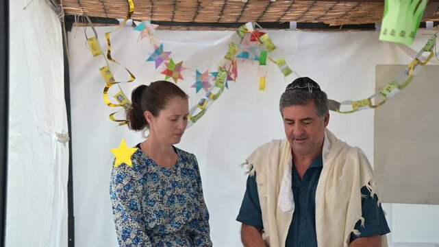 Jewish man and woman blessing on the four species are four plants: the etrog, lulav, hadass, and aravah, mentioned in the Torah as being relevant to the Jewish holiday of Sukkot.