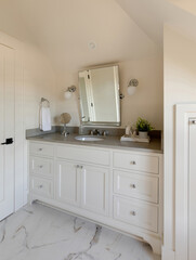 A modern bathroom with white vanity, countertop, mirror, and light fixtures. Pictured in a traditional cottage in Carlton, Oregon.