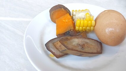 some pieces of boiled banana, boiled corn and boiled sweet potato. healthy food concept.