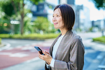 屋外でスマートフォンを持つビジネスウーマン