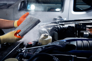 Maintenance of car air conditioning systems A mechanic holds a dusty car air filter to check for cleanliness, dirt, or repair heating problems or change the filter.