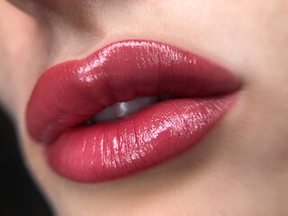 Fototapeta premium permanent makeup on the lips of a young woman of a delicate peach shade close-up, a girl after a cosmetic procedure with smooth and clean healthy skin. 