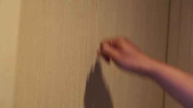 Man's hand knocking at the hotel's door with his knuckles