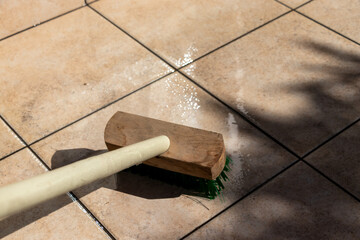 屋外のタイルをデッキブラシでこする