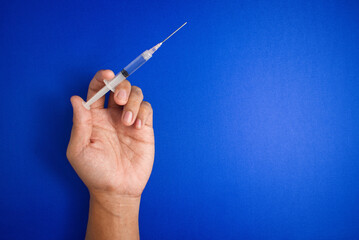 close up of male hands holding syringe isolated on blue background