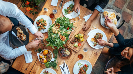 A vibrant dining scene featuring variety of delicious dishes on wooden table. Friends gather around, sharing food and enjoying each others company in warm, inviting atmosphere