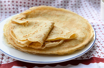 traditional french pancake homemade- folded crepe in a plate on a red and white tablecloth