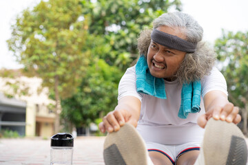 front view of a curly-haired Indonesian man who struggles to stretch his legs before exercising, the concept of a healthy lifestyle, warming up and cooling down before or after exercise.