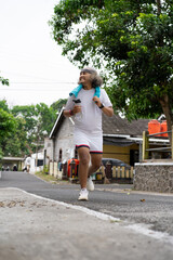 man jogging in the morning carrying a towel and tumbler, healthy lifestyle concept