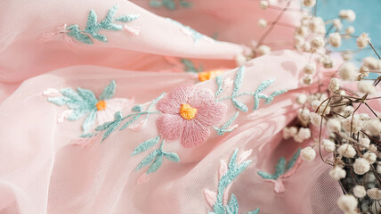Soft flowing fabric with delicate floral embroidery in pastel colors, creating gentle and serene atmosphere. intricate details of flowers and leaves enhance fabrics beauty