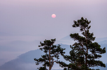 Southern Urals in summer: sunrise. The red sun through a veil of smoke from forest fires.