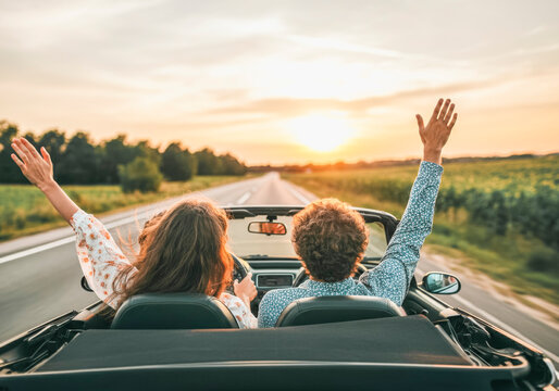 Summer road trip adventure at sunset - joyful couple in convertible
