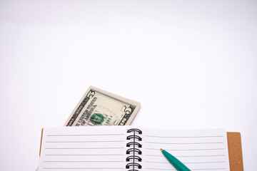Five dollar bill is sitting on top of a spiral notebook
