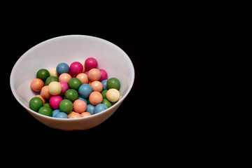 Bowl of colorful candy is on a black background