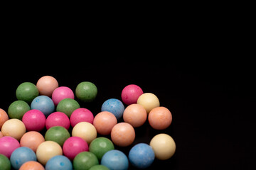 Bunch of colorful candy balls are spread out on a black background