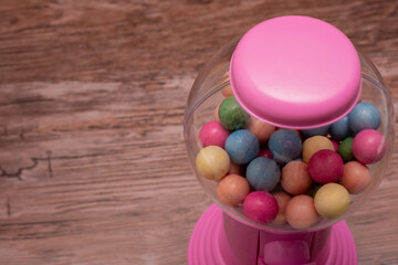 Pink gumball machine with a clear glass container full of colorful gumballs