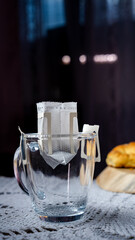 Glass cup with an open coffee filter ready for brewing on a decorated table