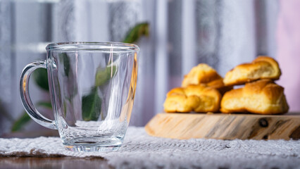 Waiting for coffee, empty glass beside rolls on wooden table
