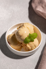A balls of peach ice cream with a mint leaf in a beautiful creamer