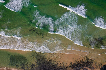 Aerial views of waves from the sea crashing against the beach in Fingal Head, New South Wales, Australia