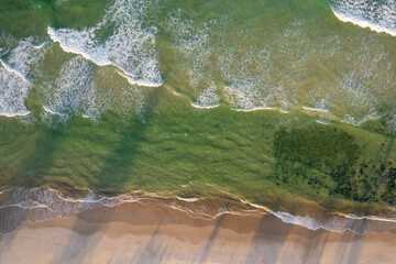 Aerial views of waves from the sea crashing against the beach in Fingal Head, New South Wales, Australia