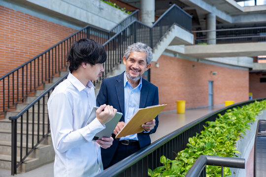Asian senior professor is giving advice  to the college student on the research thesis while sitting in the university faculty for education, academic and business