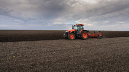 Fototapeta premium Tractor on the field during sunset.
