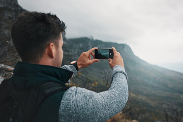 Man, hiking and phone on mountain for photography, adventure memory and scenery for social media. Fitness influencer, tech screen and photo in nature for travel blog, online journal or follower guide