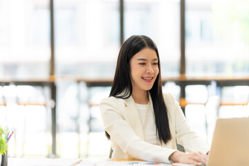 Focused and Confident: A young businesswoman, radiating confidence and professionalism, works diligently on her laptop, showcasing the drive and determination of modern entrepreneurship.  