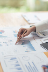 Analyzing Financial Data: Close-up of a hand meticulously reviewing financial charts and graphs,...