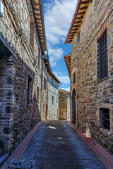 The narrow alleyways of Collemancio reveal beautifully preserved medieval architecture set against the backdrop of a clear blue sky in Umbria. Village Collemancio - Italian national heritage