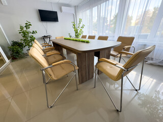A large wooden table with a green plant in the middle and eight chairs around it