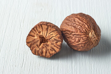 two nutmegs on a light wooden table