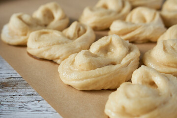 Raw buns on baking paper, close-up, selective focus