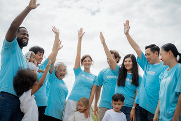 A group of people wearing blue shirts with the word volunteer on them. They are all smiling. environment, clean, wind turbine, volunteer, community, teamwork, social, care, nature
