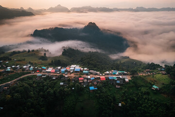 Fototapeta premium Aerial view of Morning fog and mountains with a rural village and sunrise from above