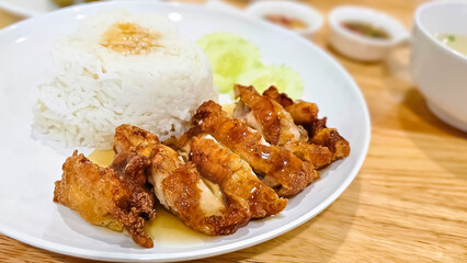 Rice and crispy fried chicken fillet with sauce on white plate and wooden table background