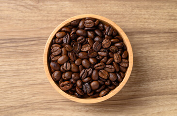 roasted coffee bean (Arabica coffee) in bowl on wooden background, Table top view