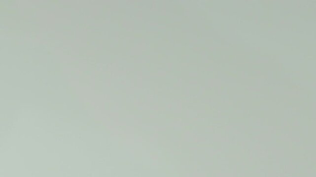 close up on crimson liquid that falls from top to bottom on a white background, can be used to advertise products with crimson elements
