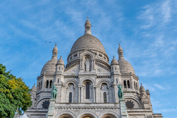 The ancient Basilica of the Sacred Heart in Montmartre, Paris, France, with birds flying near the...