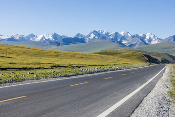 Asphalt highway road and green grassland with mountain natural landscape under blue sky. road trip.