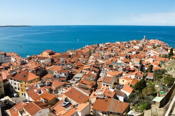 Aerial view of Piran with red rooftops and sea.