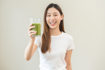 Green detox juice concept, Beautiful asian young woman hand holding vegetable smoothie glass for...
