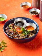 Lemongrass Grilled Chicken Inasal Rice with dipping Sauce and Green Onion isolated on orange background closeup side view of fast food meal