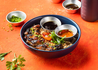 Lemongrass Grilled Chicken Inasal Rice with dipping Sauce and Green Onion isolated on orange...
