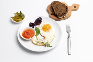 Fried egg on the plate, pickled cucumbers and bread,