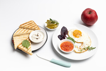 Fried egg on the plate, pickled cucumbers and bread,
