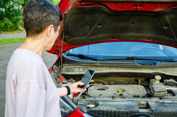 woman photographs breakdown in the open hood of a car